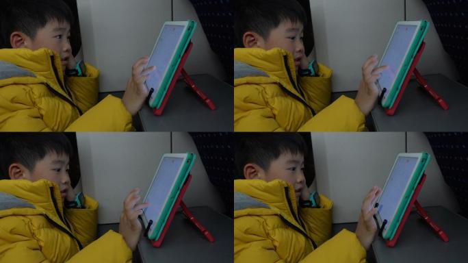 男孩在高铁上玩平板电脑