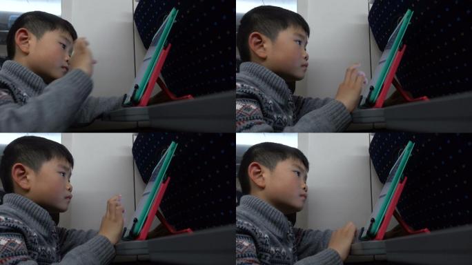 男孩在高铁上玩平板电脑
