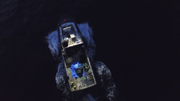 无人机拍摄的一名男子夜间驾船穿越海面