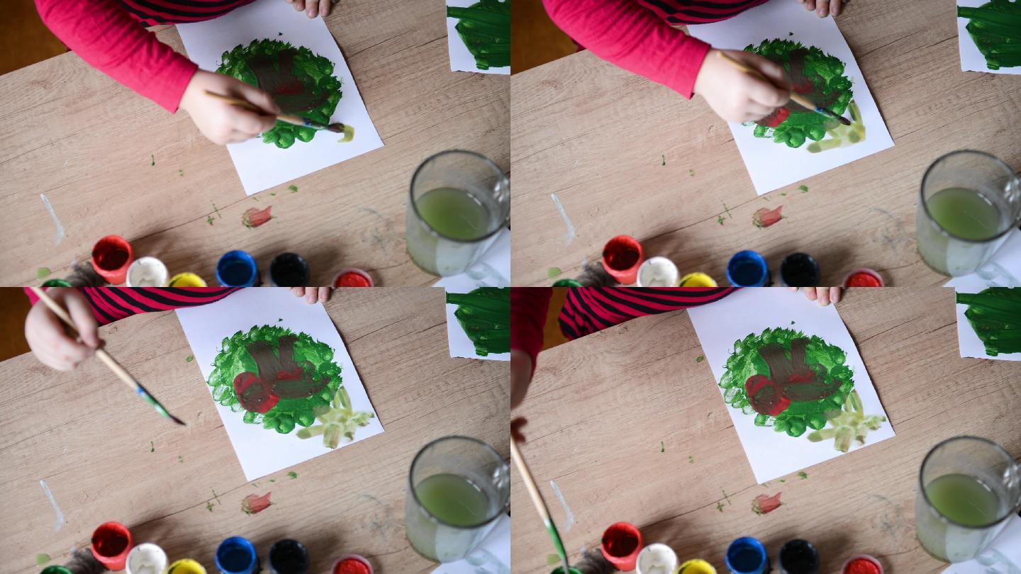 孩子在纸上的木桌表面画水彩画。