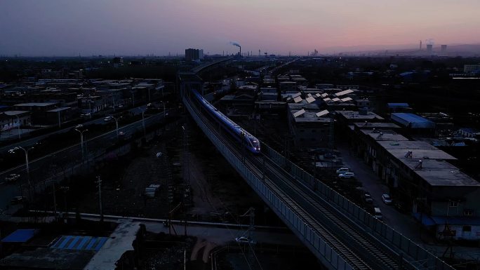 夜幕下，高铁穿过铁路和公路立交桥。