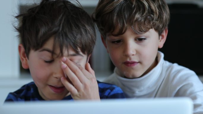 孩子在揉眼睛的同时盯着电脑屏幕。