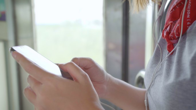 女性在坐火车时用智能手机听音乐放松