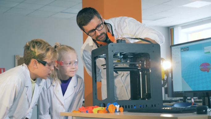 教正在向孩子们演示3D打印机的工作过程。