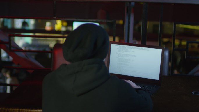 男子坐在笔记本电脑在键盘上输入代码