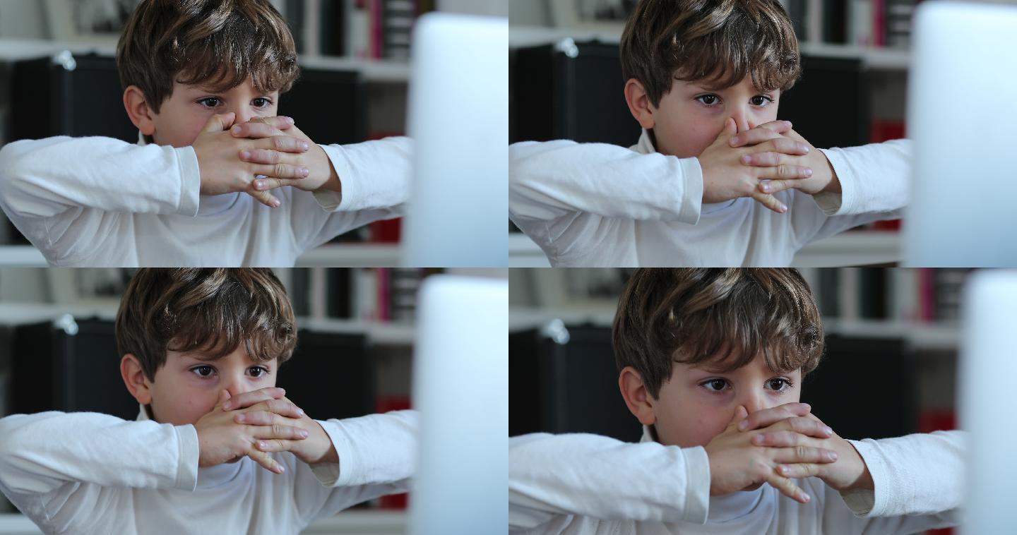 男孩看着电脑带着紧张的表情。