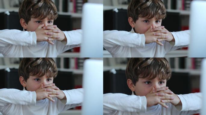 男孩看着电脑带着紧张的表情。