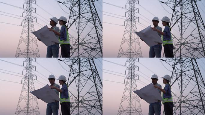 两名电气工程师在高压塔附近工作。