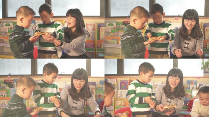 儿童和幼儿园老师在教室里吃披萨