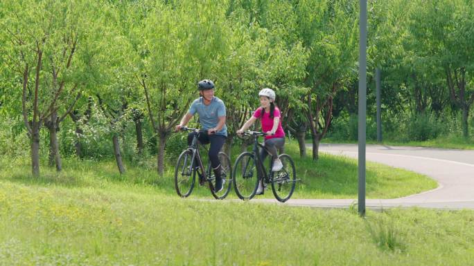 开心的中老年夫妇在公园骑自行车