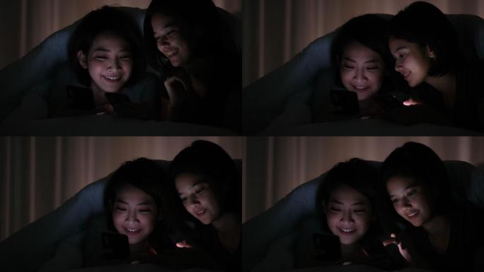 两个女孩躺在床上玩手机