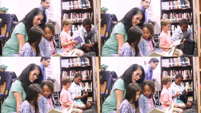 老师在图书馆里为小学生朗读一本书。