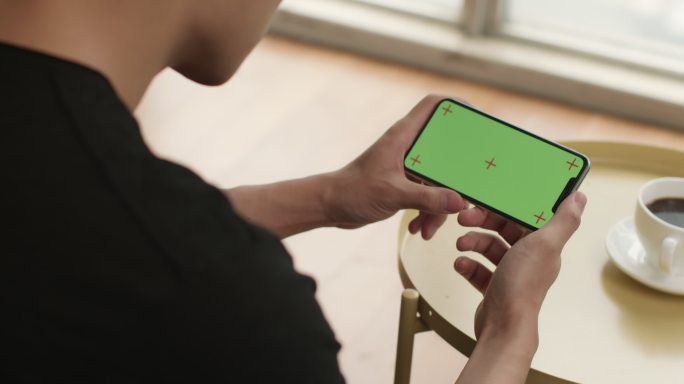 年轻男子在家使用绿色屏幕的手机