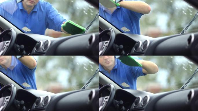 一个男子在清洗他的汽车挡风玻璃。