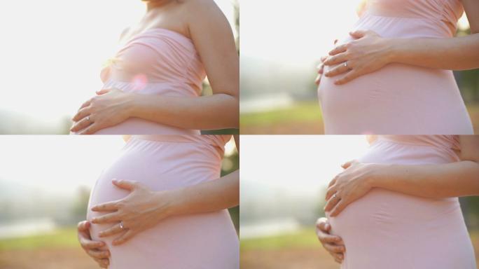 一名孕妇俯身抚摸自己的腹部