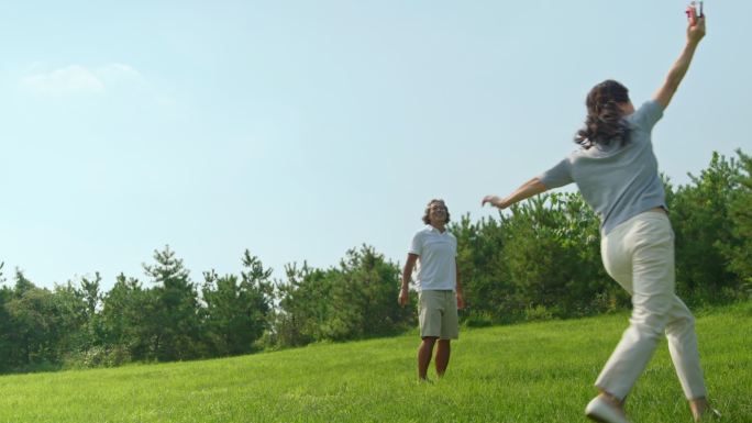 开心的中老年夫妇在草地上放风筝