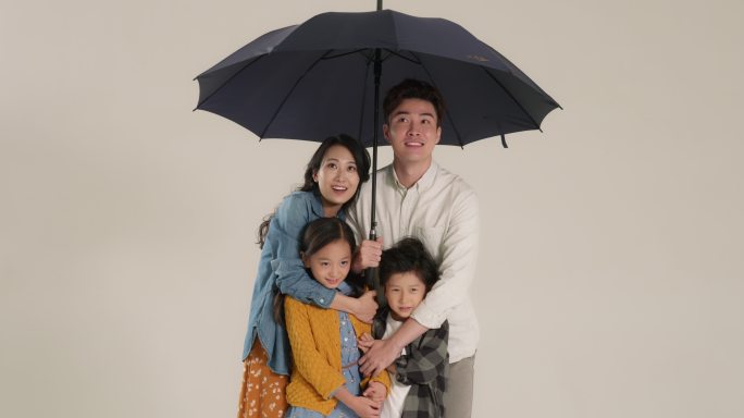 快乐的年轻家庭打着雨伞