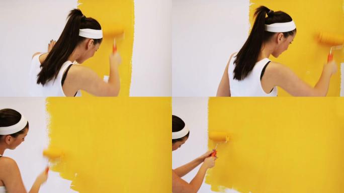 漂亮的女人用油漆滚筒粉刷家里的内墙