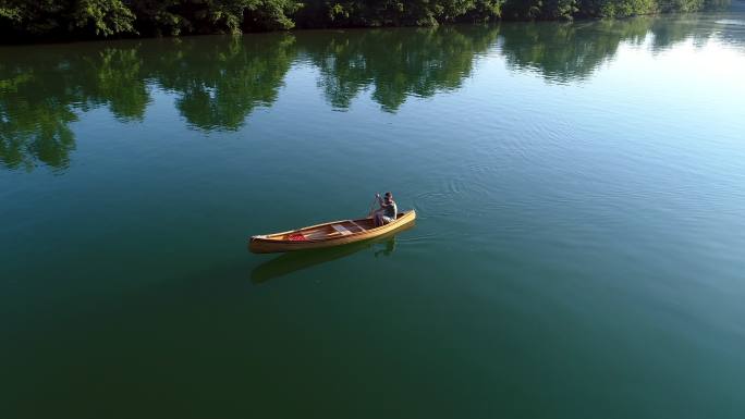 一个男子在平静的湖面上划着独木舟。