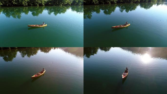 一个男子在平静的湖面上划着独木舟。