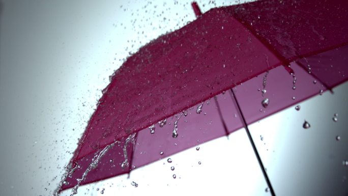 雨慢慢地落在粉红色的伞上