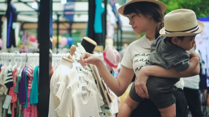 妇女和她的儿子在跳蚤市场上看衣服。