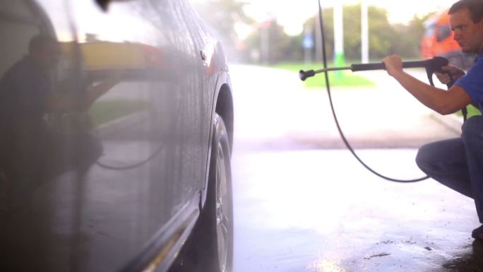 一名男子用高压喷水喷头冲洗他的汽车