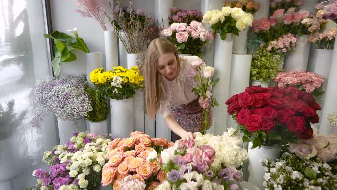 一个女人在花店里收集一束花。