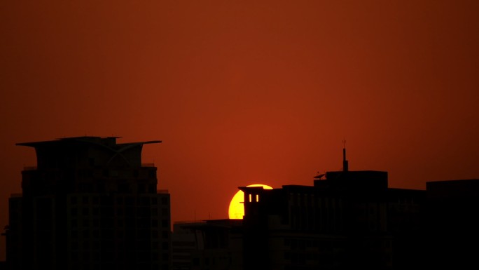 红日落在建筑物后面的画面。