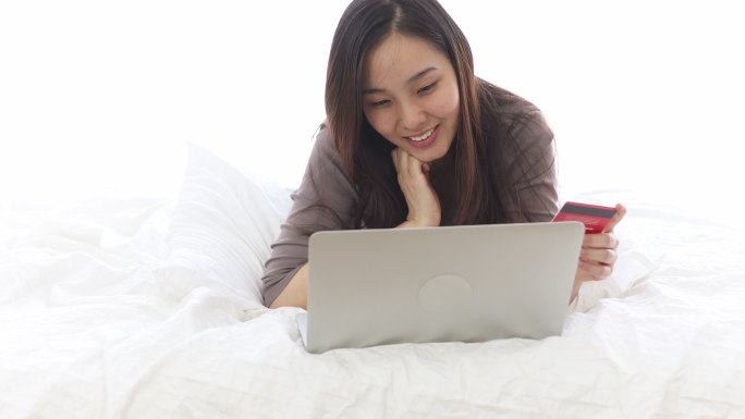 女子在卧室用笔记本电脑网上购物