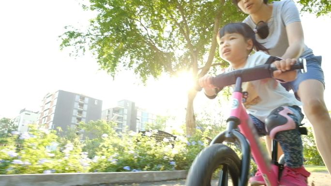 女孩和她的妈妈在公园骑自行车