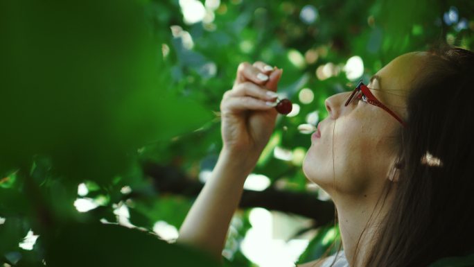 这位年轻女子喜欢吃树上的樱桃。