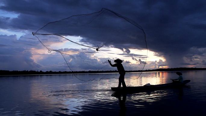 渔民在木船上撒网捕鱼