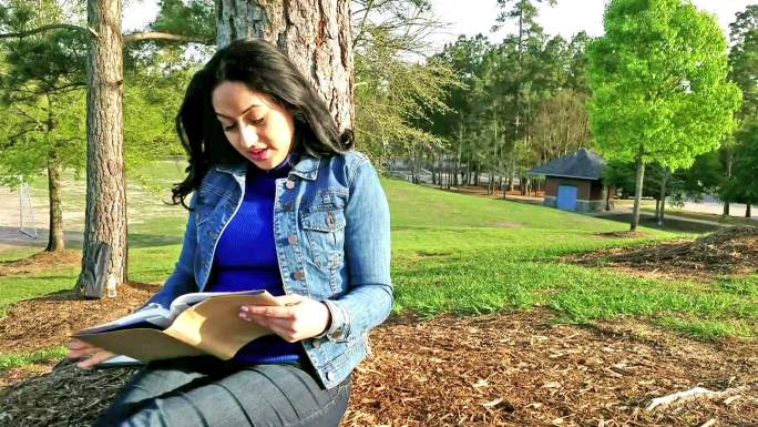 一位妇女在公园里户外读书。