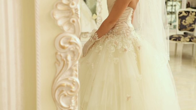 镜子里的新娘，她穿着婚纱，戴着白手套。