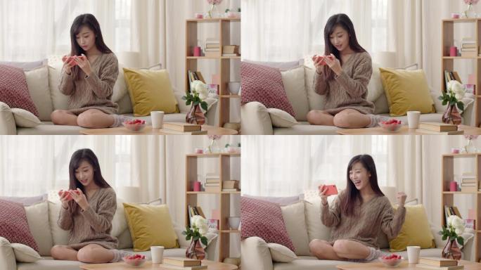年轻女士在沙发上玩手机游戏
