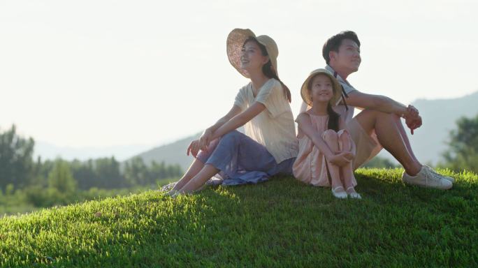 快乐的年轻家庭坐在草地上