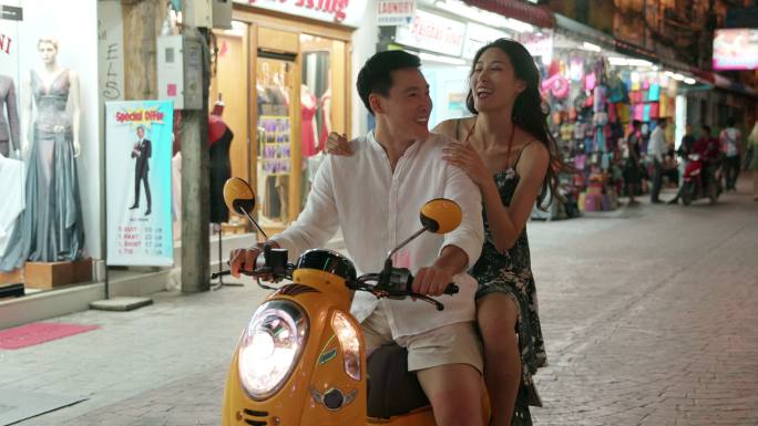 快乐的年轻情侣骑摩托逛夜市
