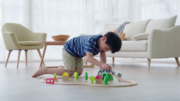 快乐的小男孩在客厅玩火车玩具