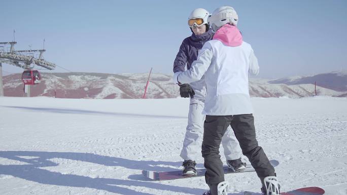 年轻男子教女朋友单板滑雪