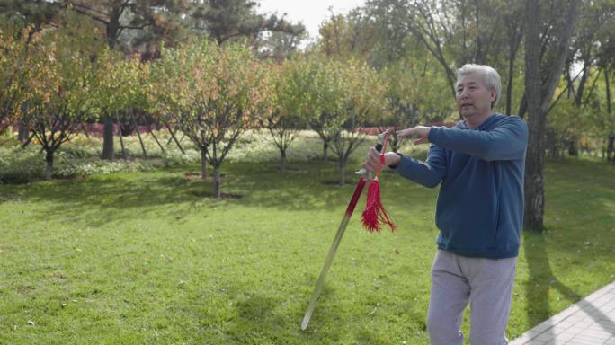 快乐的老年男子在公园舞剑