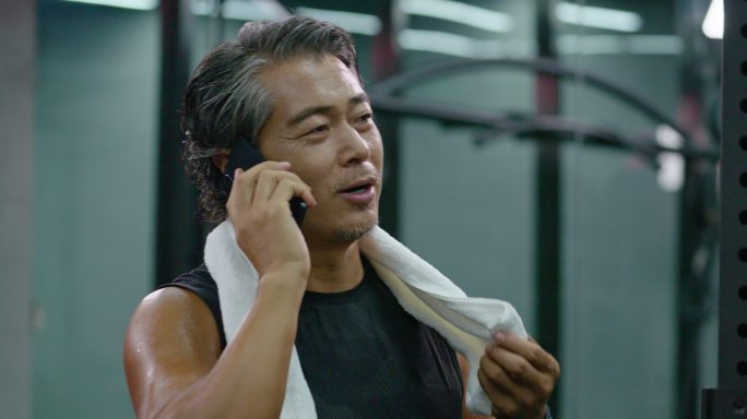 成熟男士在健身房使用手机