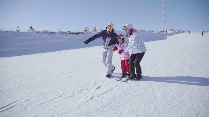 年轻父母教女儿滑雪