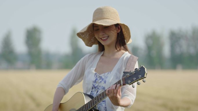 年轻女子在麦田里弹吉他