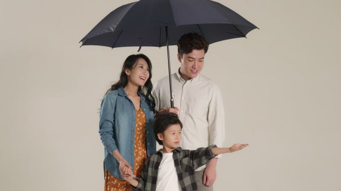 快乐的年轻家庭打着雨伞