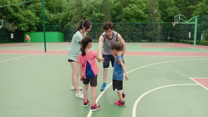 年轻家庭在篮球场打篮球