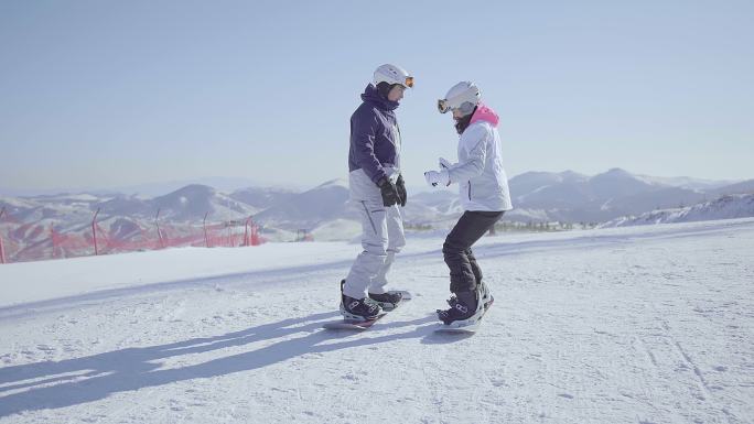 年轻男子教女朋友单板滑雪