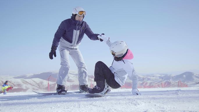 年轻男子教女朋友单板滑雪