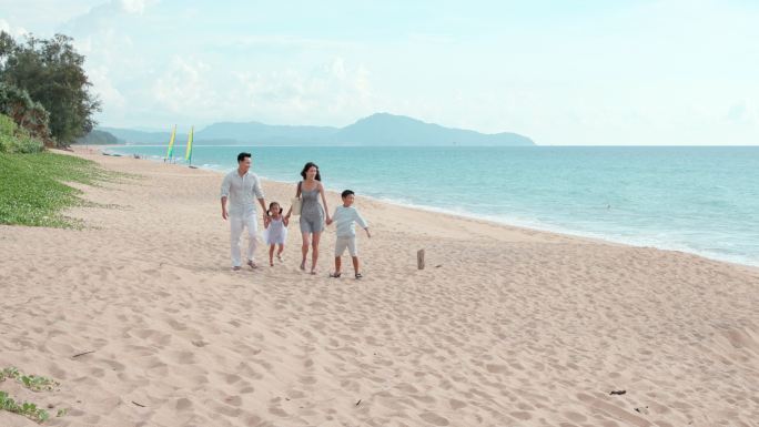 快乐的年轻家庭在沙滩散步