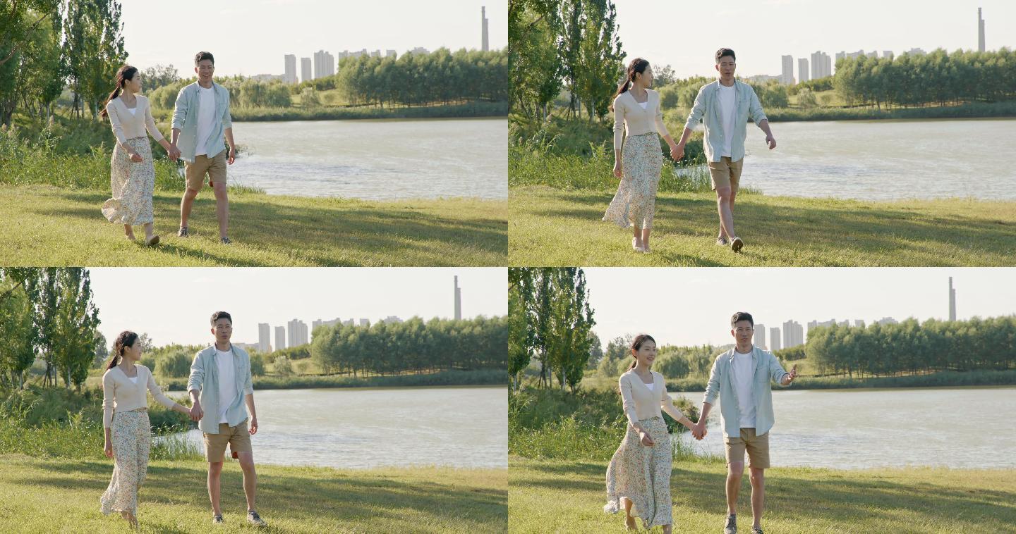 快乐的年轻情侣手牵手在草地上散步